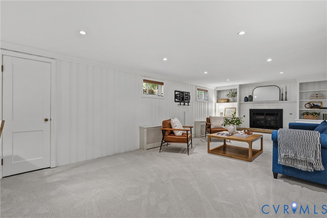 Interior space featuring vertical wood-panelled walls, recessed ceiling lighting, a stone-surround fireplace, and flanking built-in shelving