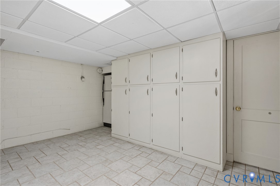 Built-in floor-to-ceiling cabinetry, tiled flooring, drop ceiling with recessed lighting, and painted masonry walls