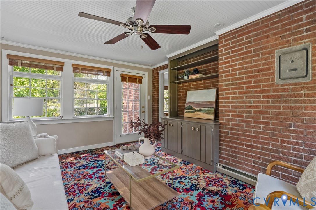 Exposed brick wall featuring built-in cabinetry with shelving, beadboard ceiling, ceiling fan, and multi-pane windows