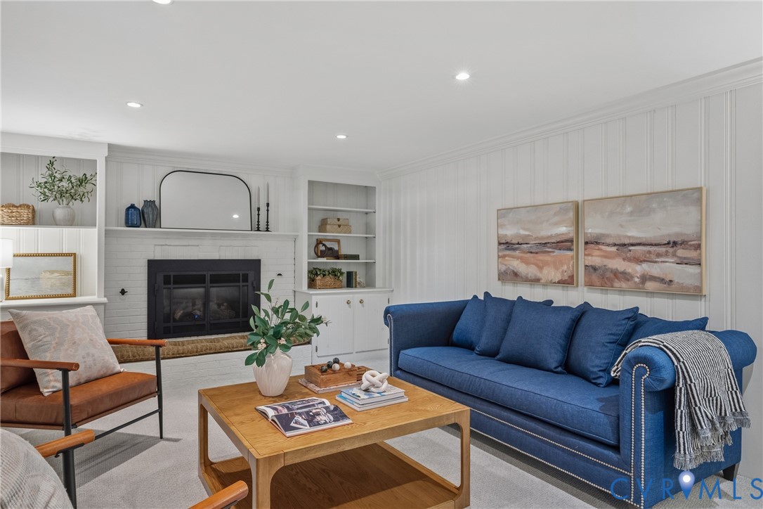 Fireplace with custom built-in shelving, vertical wood wall paneling, and recessed lighting