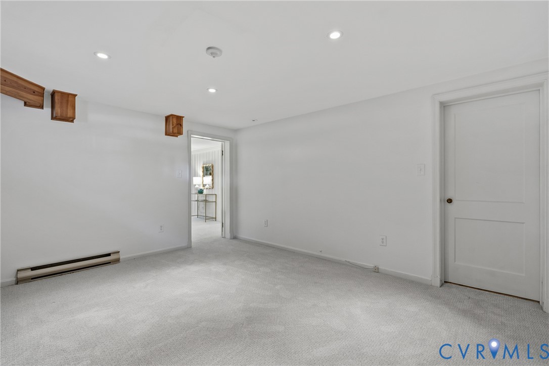 Neutral-toned carpeting, recessed ceiling lighting, two-panel interior door, and exposed wood structural accents