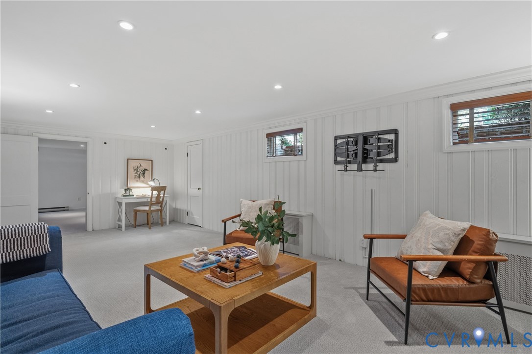 Vertical wood-paneled walls, neutral carpeting, recessed ceiling lighting, and multiple horizontal windows with wood-tone framing