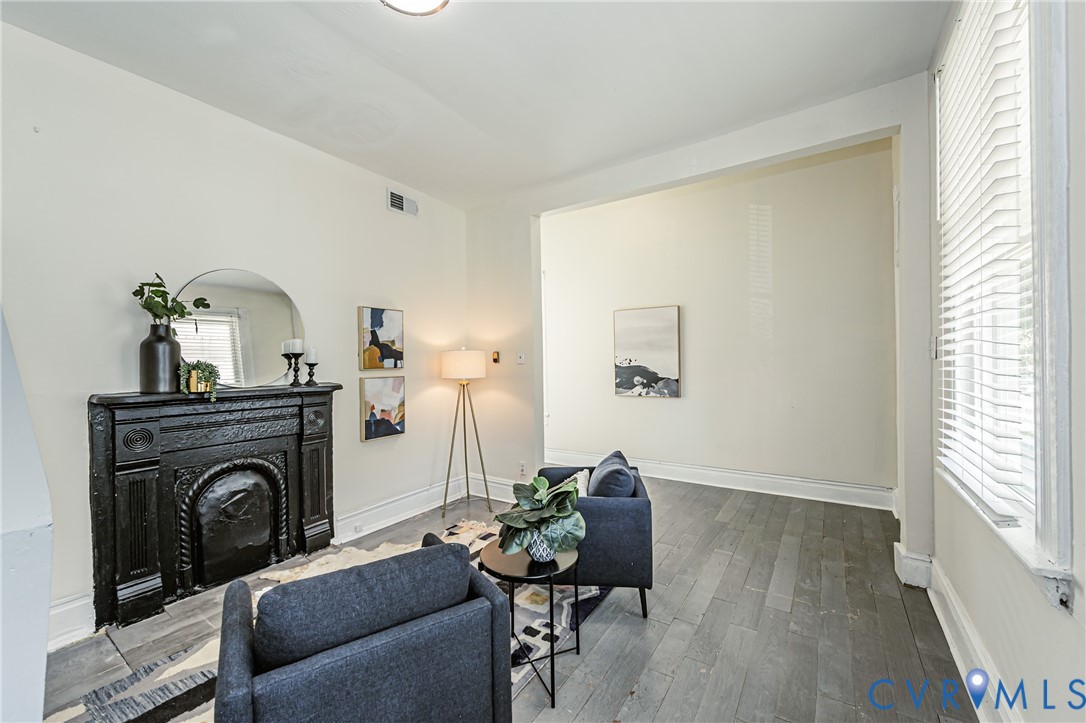 Ornate cast-iron fireplace surround, neutral wall finishes, wood-finish flooring, and horizontal window blinds