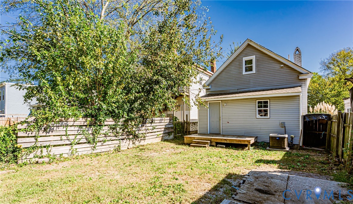 Exterior rear elevation featuring light-colored horizontal siding, a wooden deck, and a fenced backyard