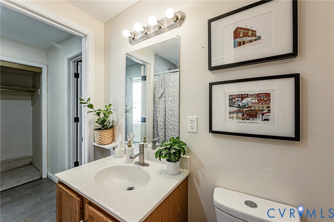 Vanity featuring a white countertop with an integrated basin, wood-finish cabinetry, a polished metal faucet, and a four-bulb wall-mounted light fixture