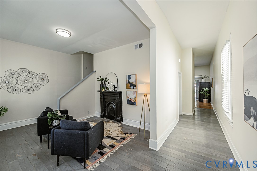 Living area featuring wood-finish flooring, a decorative black cast-iron fireplace surround, a staircase with a partial wall, and a flush-mount ceiling light fixture