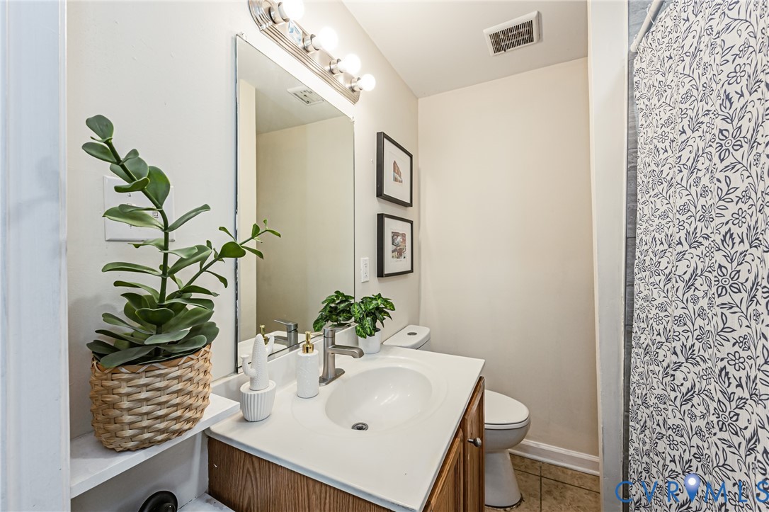 Bathroom featuring a vanity with a white countertop and integrated oval sink, wood-finish cabinetry, a large wall-mounted mirror, and a multi-bulb light fixture