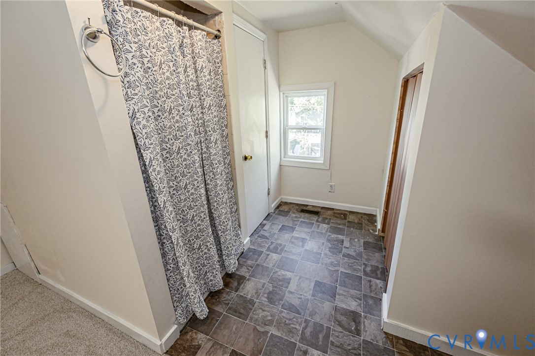 Multi-tonal stone-look tile flooring, single-pane window with white trim, and interior wood-panel door