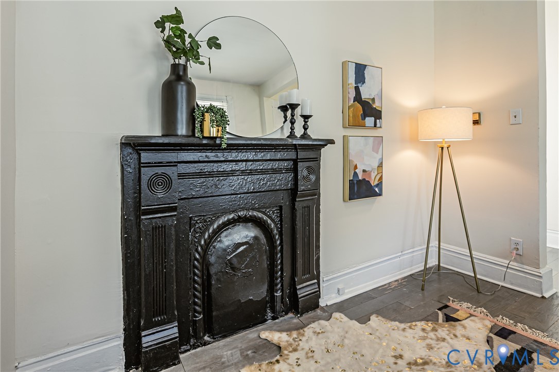 Ornate black metal fireplace mantel featuring classical relief detailing and wood-finish flooring