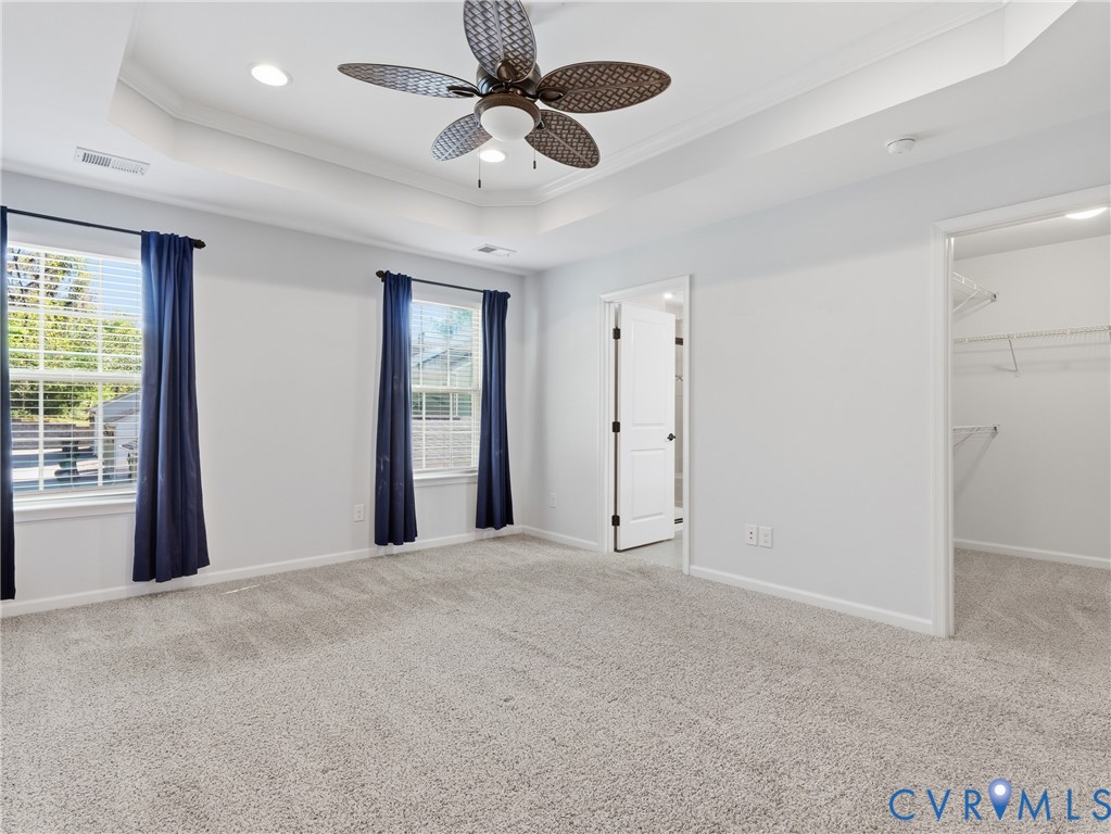 Generously sized primary suite with plush carpeting, walk-in closet, and private ensuite