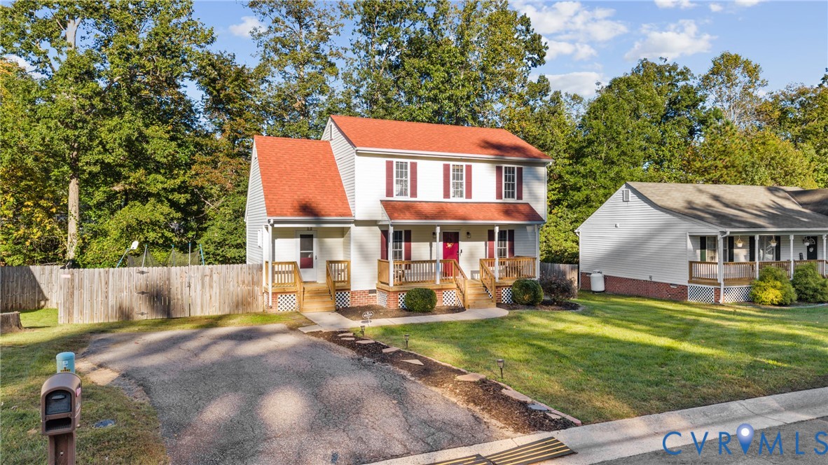 Two-story home with a red roof, light-colored siding, shuttered windows, a wood-framed covered front porch, and a paved driveway