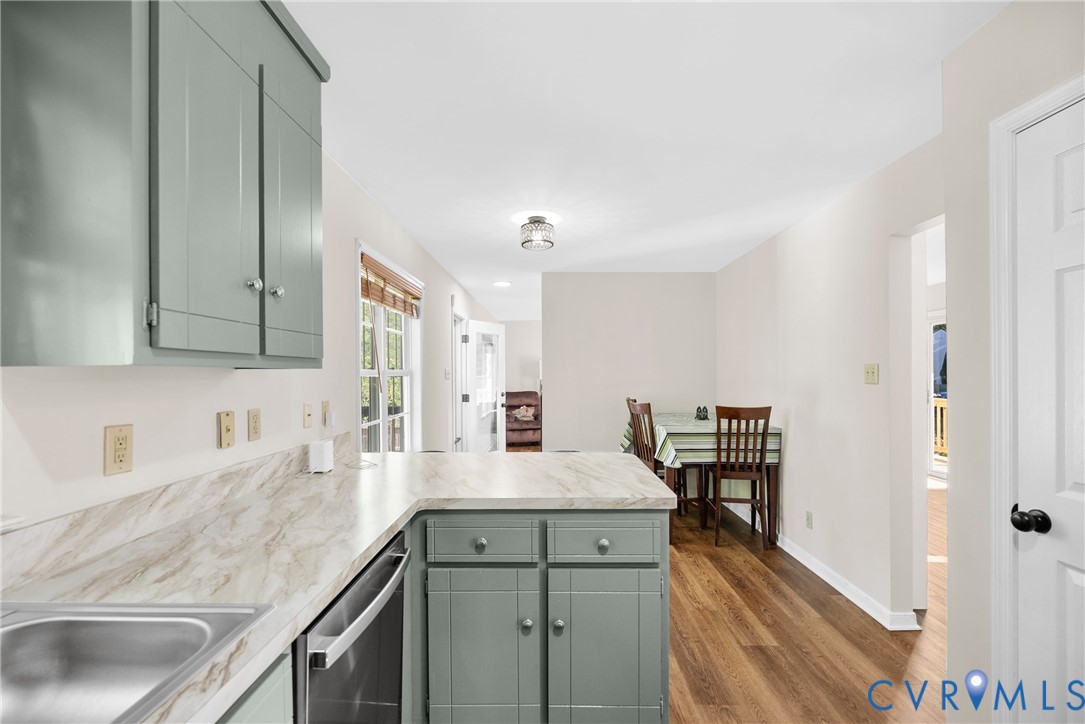 Kitchen featuring shaker-style cabinetry, stone-patterned laminate countertops, stainless steel sink, and wood-finish flooring Kitchen featuring shaker-style cabinetry, stone-patterned laminate countertops, stainless steel sink, and wood-finish flooring
