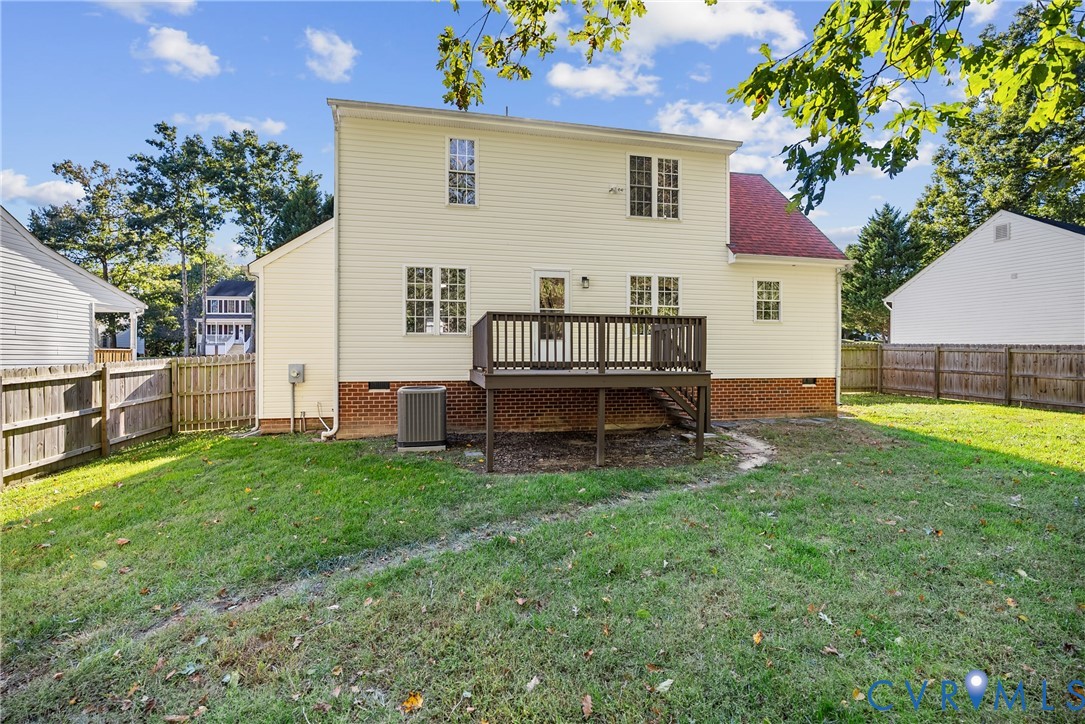 Rear exterior featuring a tiered deck, horizontal vinyl siding, brick foundation, and enclosed wood fencing