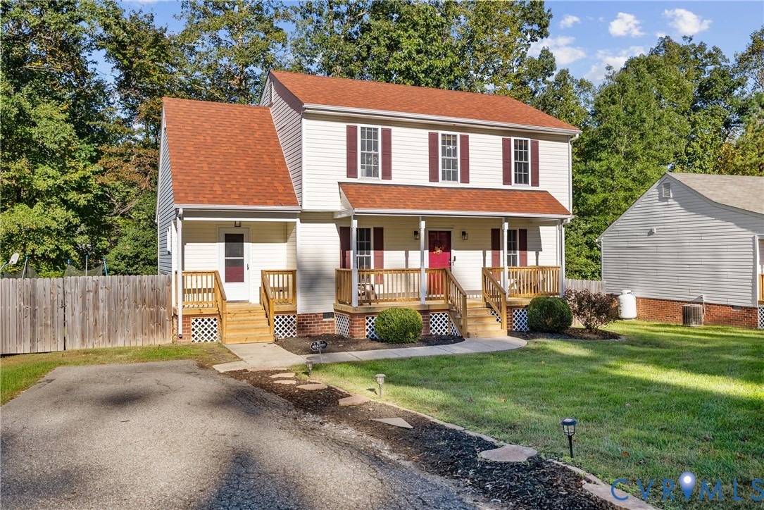 Two-story home with light siding, a shingled roof, a covered front porch featuring wooden railing, and a paved driveway Two-story home with light siding, a shingled roof, a covered front porch featuring wooden railing, and a paved driveway