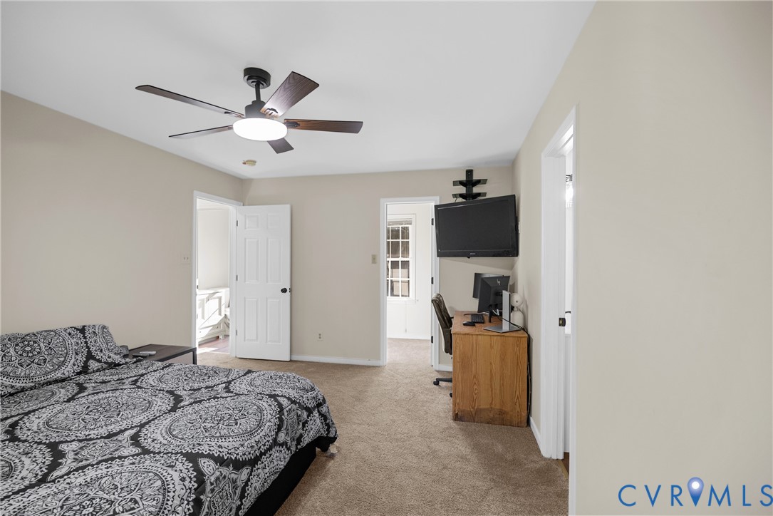 Neutral interior space featuring carpeting, ceiling fan with integrated lighting, multi-panel doors, and wall-mounted shelving