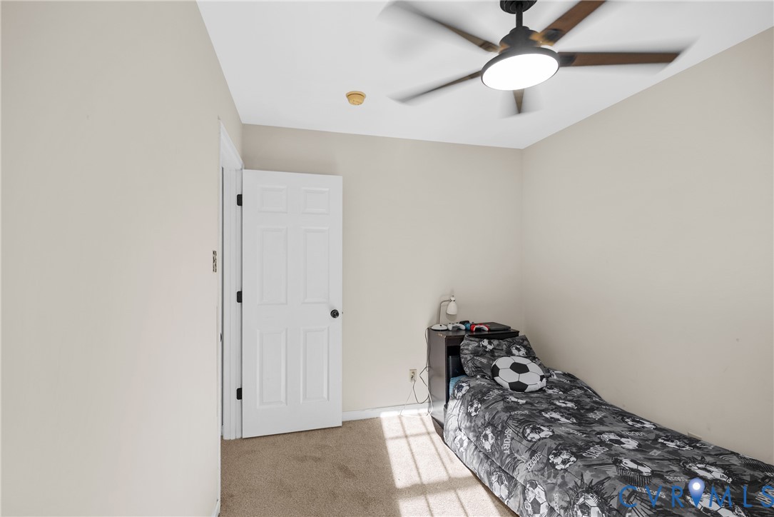 Neutral-toned interior space featuring neutral carpeting, a multi-panel door, and a ceiling fan with integrated LED lighting