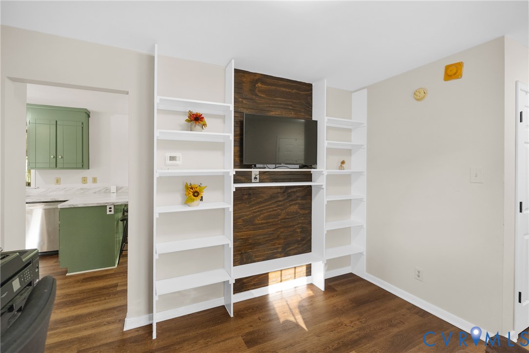 Built-in white shelving flanking a dark wood-finish accent wall with integrated television mount and wood-finish flooring