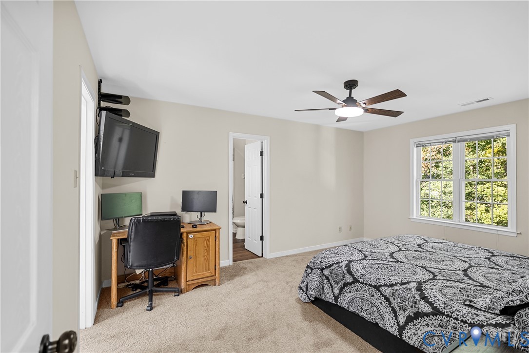 Neutral-toned interior featuring wall-to-wall carpeting, a multi-blade ceiling fan with integrated lighting, and a double-hung window