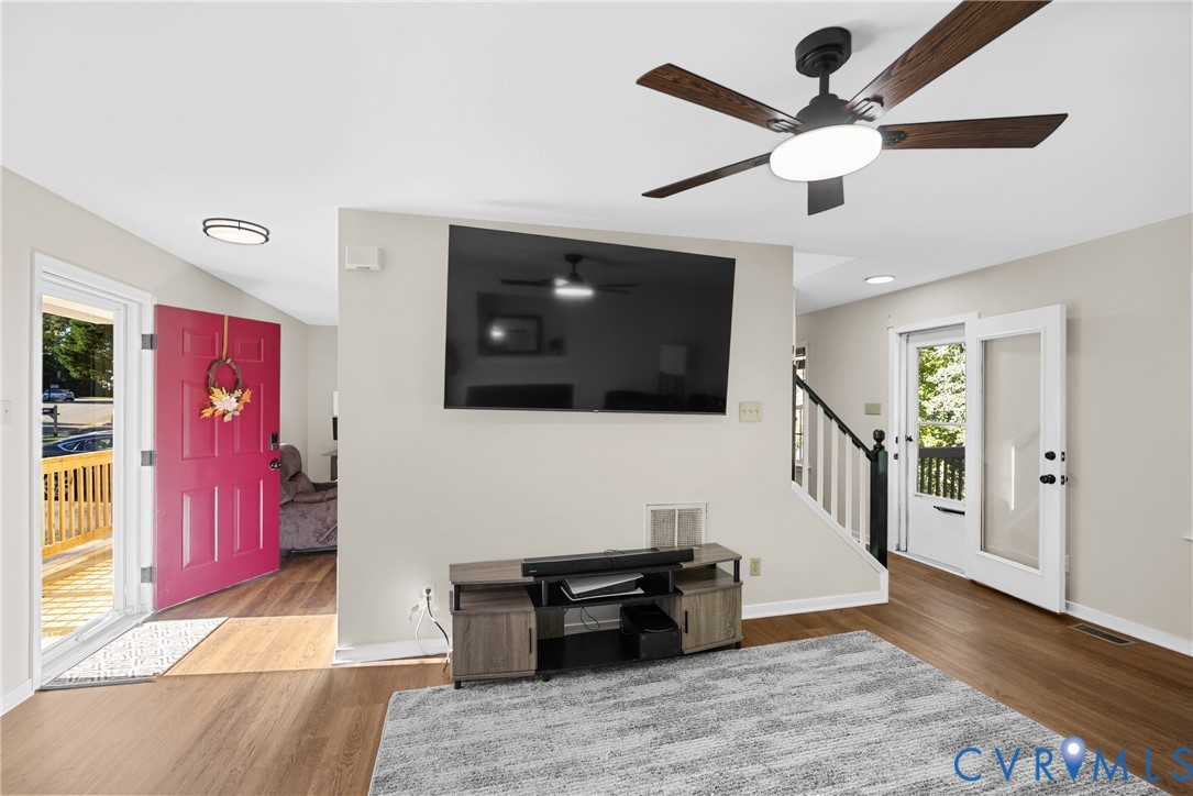 Wood-finish flooring, ceiling fan with integrated lighting, recessed lighting, and a partial staircase with a black handrail