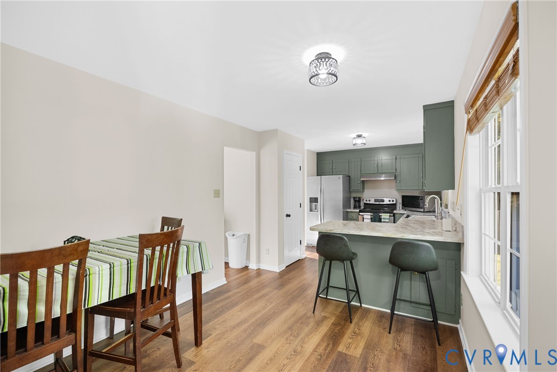 Kitchen featuring sage green cabinetry, stone-patterned countertops, wood-finish flooring, and recessed ceiling lighting
