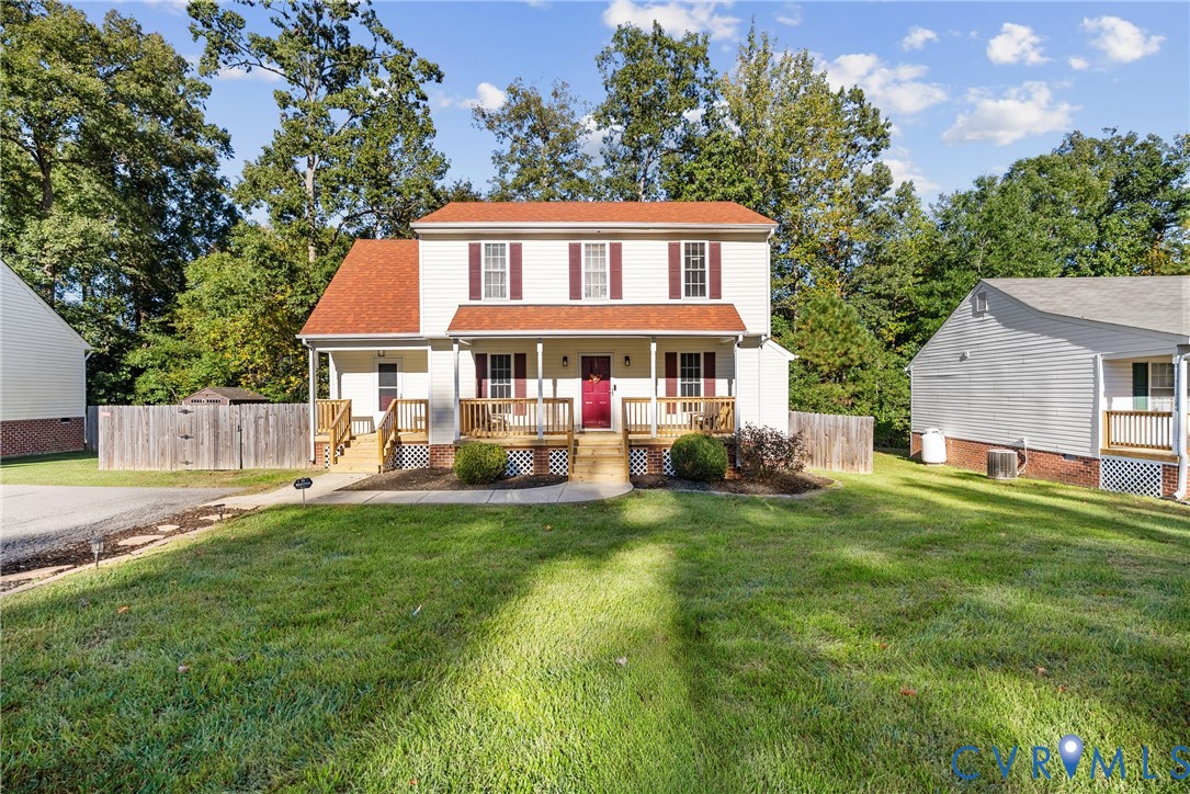 Two-story residence featuring a covered front porch, red-toned shingle roof, neutral siding, and shutter-framed windows Two-story residence featuring a covered front porch, red-toned shingle roof, neutral siding, and shutter-framed windows