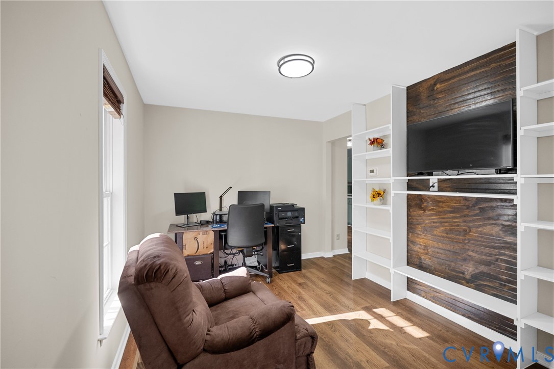 Built-in shelving units with a wood-plank accent wall, wood-finish flooring, and flush-mount ceiling lighting