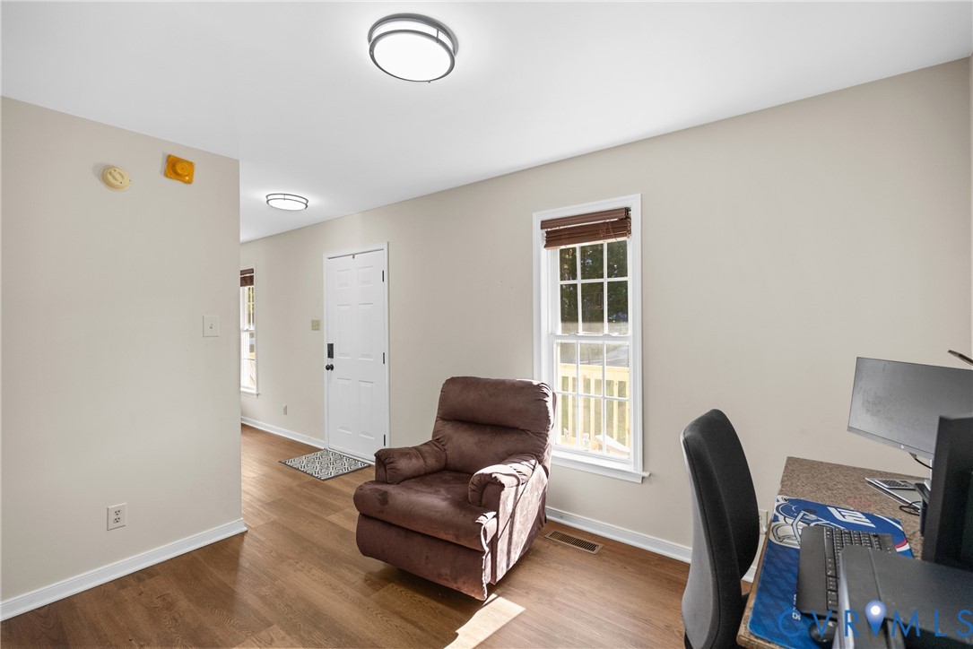 Neutral walls, wood-finish flooring, white paneled entry door, double-hung window with muntins, and flush-mount circular lighting fixtures