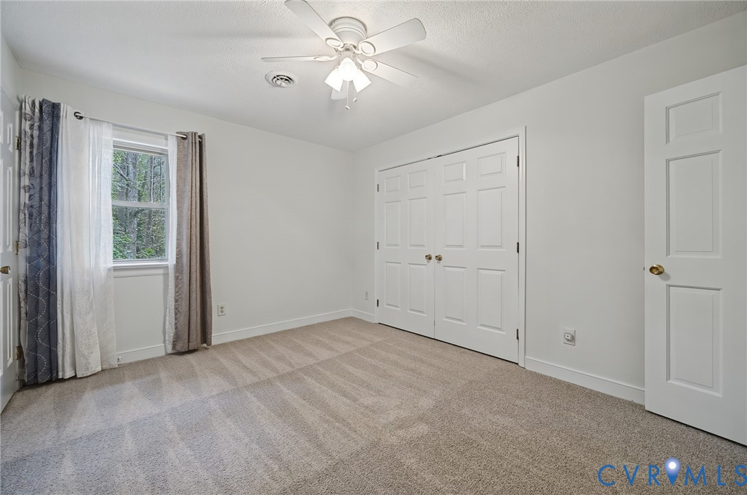 Neutral wall finishes, carpeting, ceiling fan with integrated lighting, double-door closet, and interior panel door