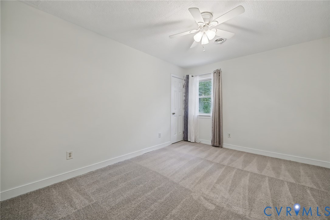 Interior space featuring neutral-toned carpeting, a ceiling fan with integrated lighting, and a single-panel interior door