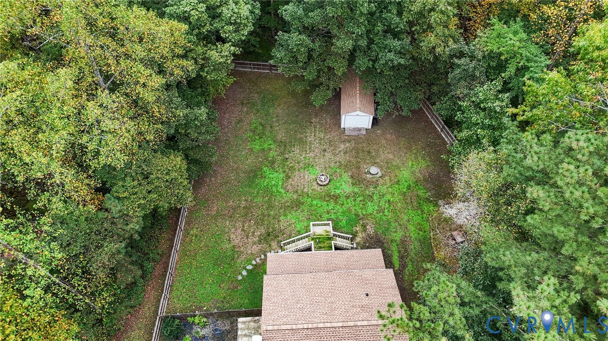 Fenced backyard featuring a detached storage shed, mature trees, and a wooden deck