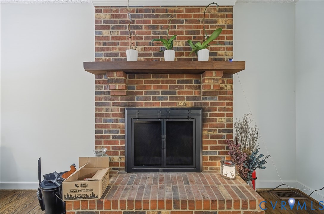 Floor-to-ceiling multi-tone brick fireplace featuring a thick wood mantel, raised brick hearth, and integrated metal firebox enclosure