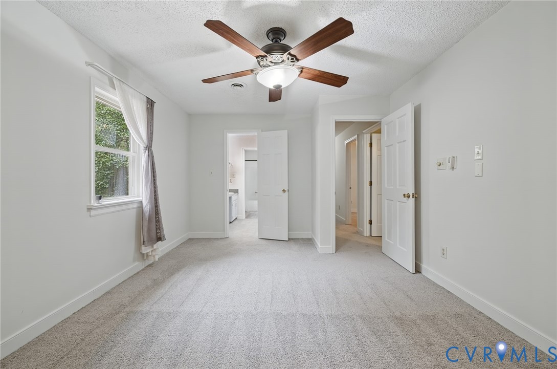 Interior room featuring neutral wall-to-wall carpeting, a multi-blade ceiling fan with integrated lighting, and a window with a single pane