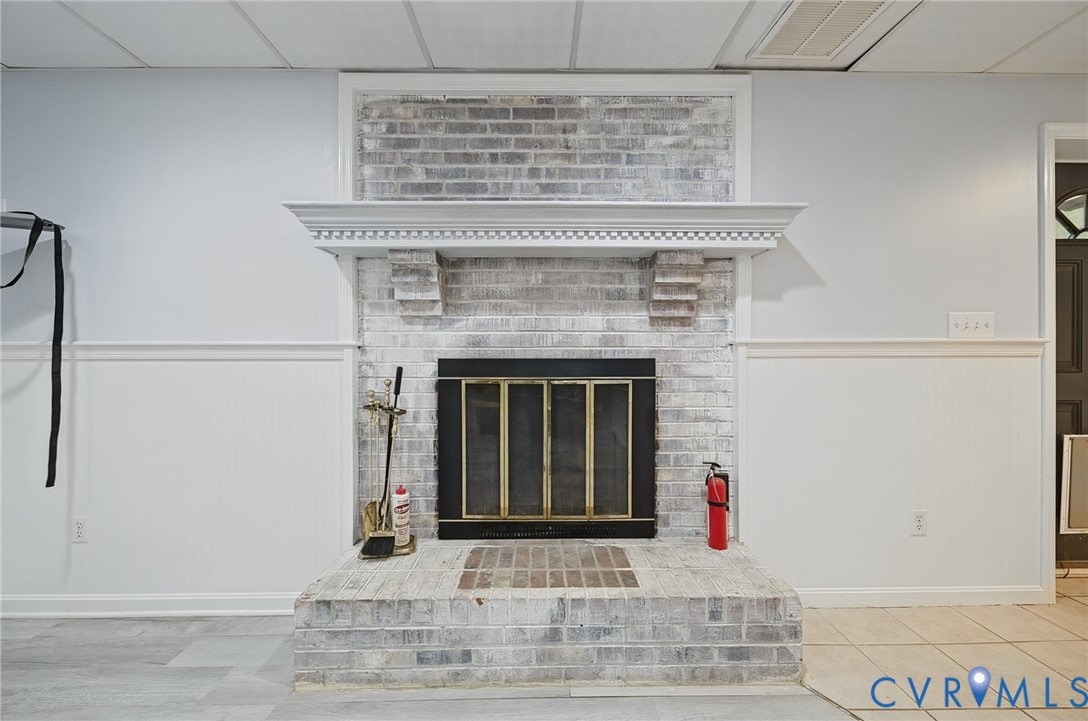 Floor-to-ceiling whitewashed brick fireplace featuring a crown-molded mantelpiece, corbel accents, and an integrated raised hearth