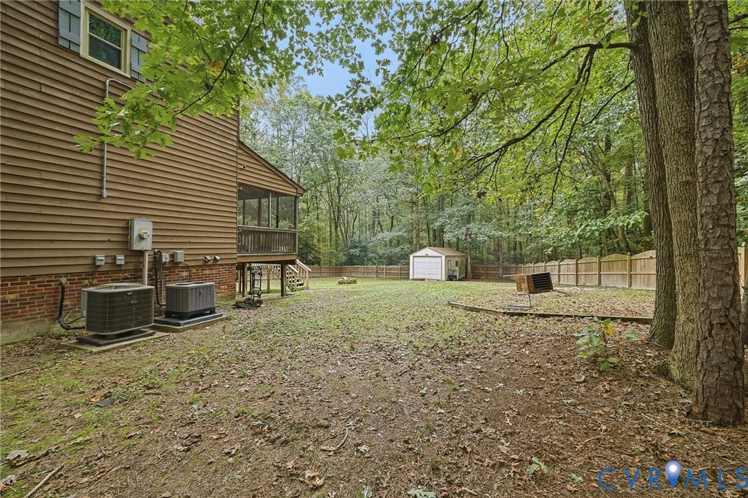 Spacious backyard featuring a wood-finish exterior, a screened porch, a detached storage building, and perimeter wood fencing