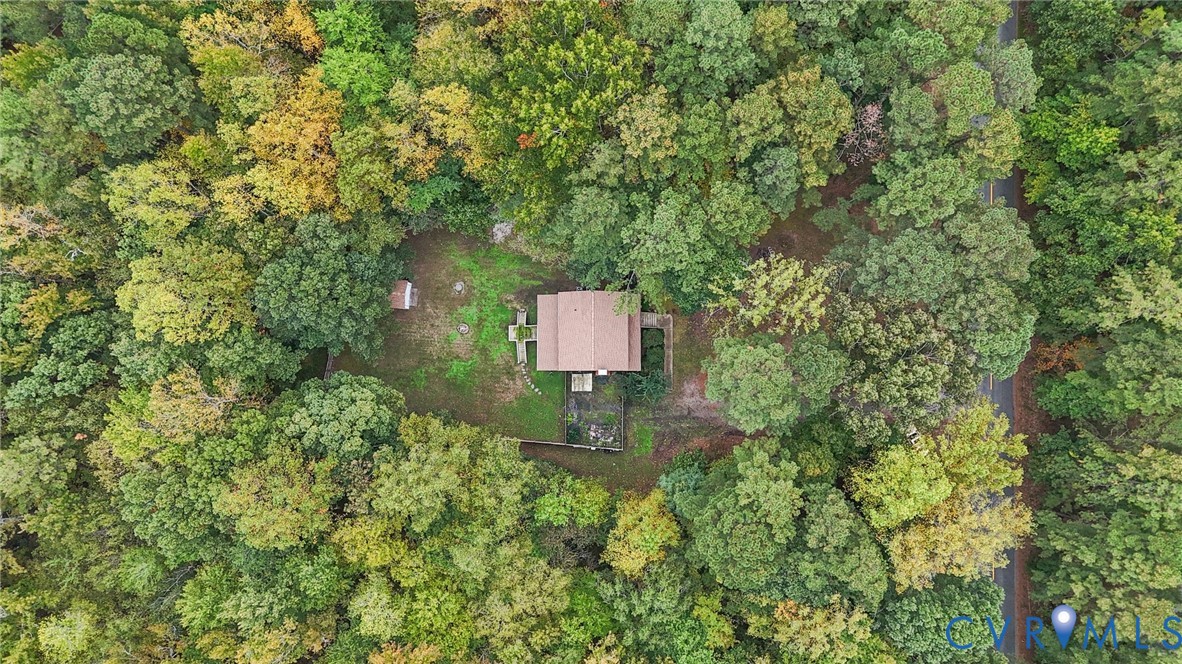 Aerial perspective of a detached residence situated on a secluded lot surrounded by mature deciduous and coniferous trees