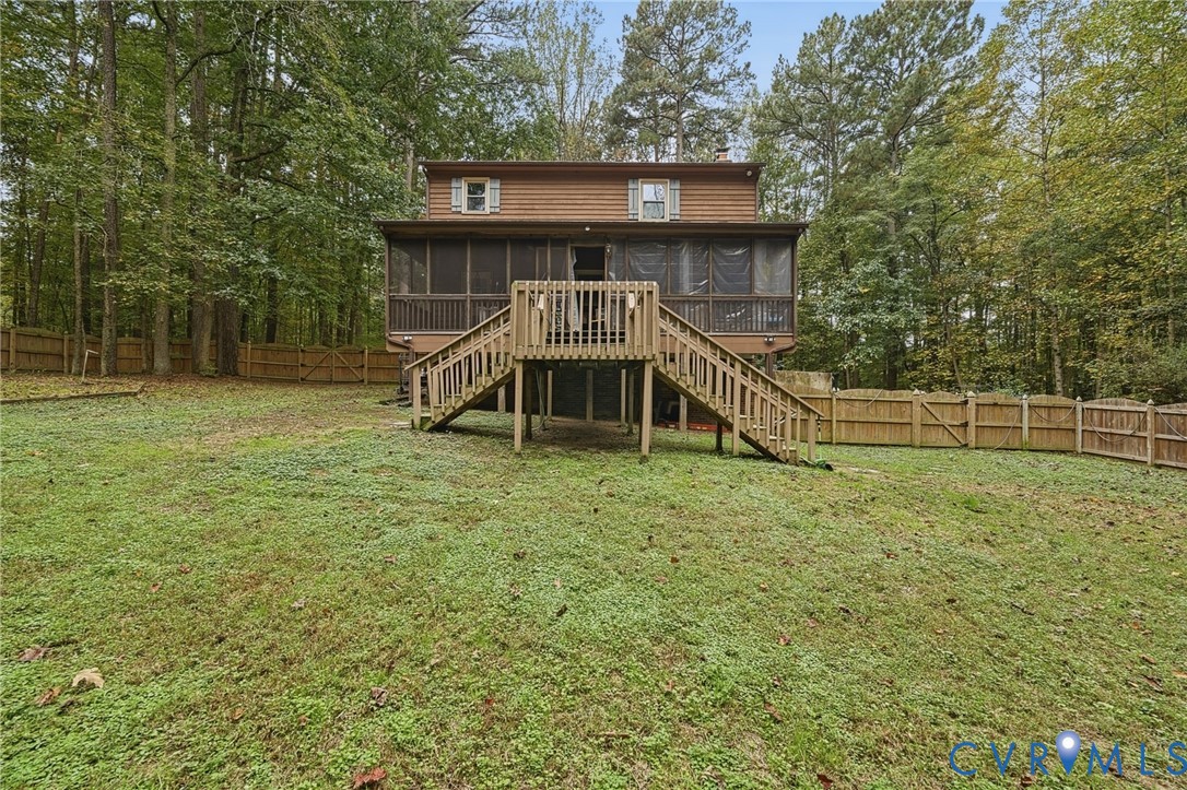Two-story exterior featuring wood siding, a screened-in porch, an elevated wood deck with stairs, and a fenced perimeter