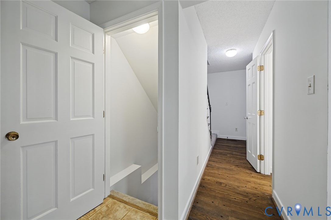 Hallway featuring wood-finish flooring, six-panel interior doors, recessed lighting, and carpeted stair access