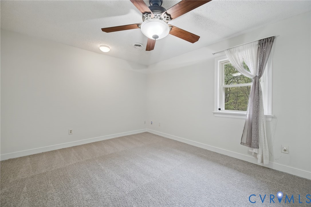 Neutral wall finishes, neutral carpeting, flush-mount lighting, and a multi-blade ceiling fan with an integrated light fixture