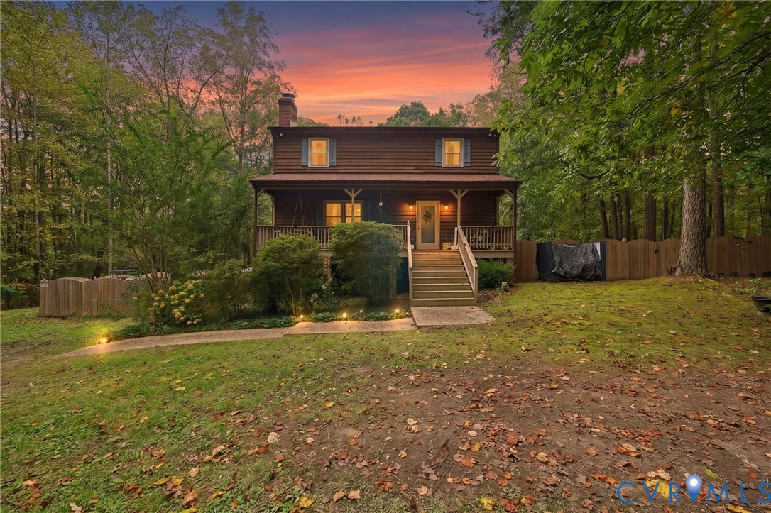 Two-story log exterior residence featuring a covered front porch, wood-slat railings, a chimney, and a fenced backyard Two-story log exterior residence featuring a covered front porch, wood-slat railings, a chimney, and a fenced backyard