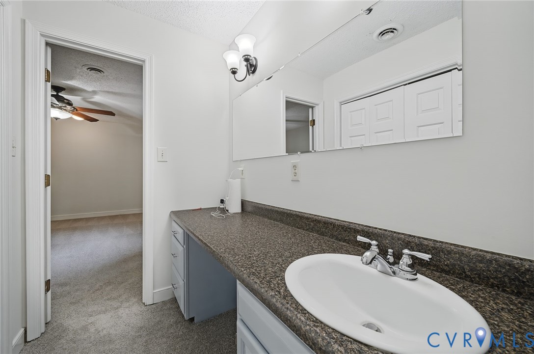 Vanity featuring a stone-composite countertop, integrated oval basin, polished chrome double-handle faucet, wall-mounted mirror, and decorative dual-light fixture