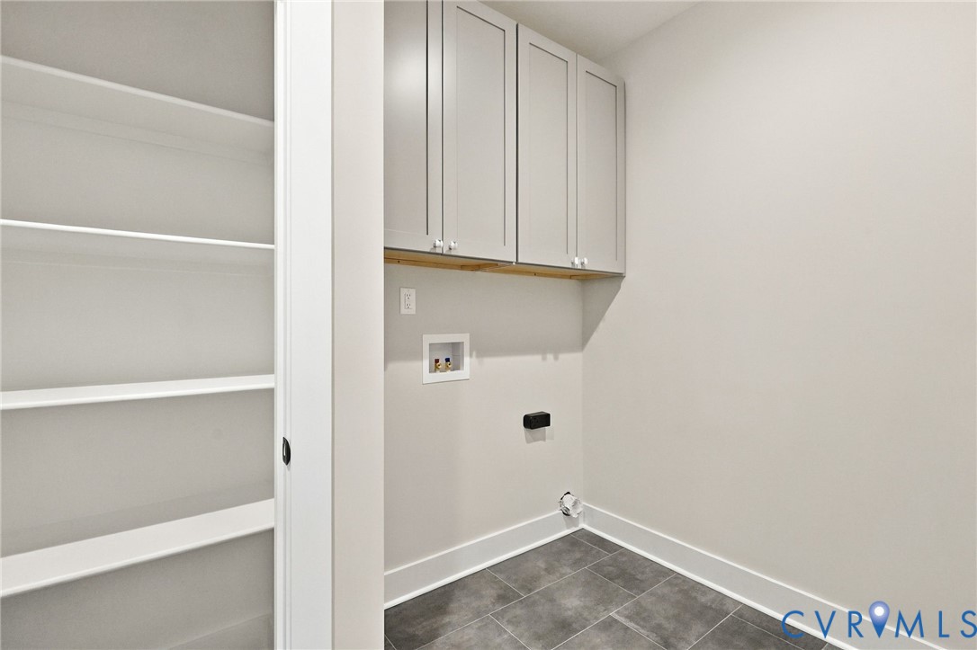 Laundry Room is Conveniently Located Down the Hall from the Primary & Includes a Closet w/Wood Shelving & Cabinets Above the Washer/Dryer Location.