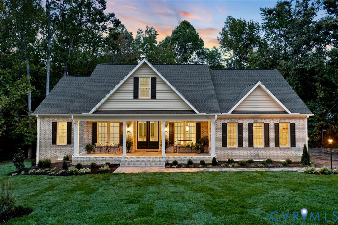 Brick exterior with a covered porch, gabled rooflines, dark shutters, and a manicured sod lawn Brick exterior with a covered porch, gabled rooflines, dark shutters, and a manicured sod lawn