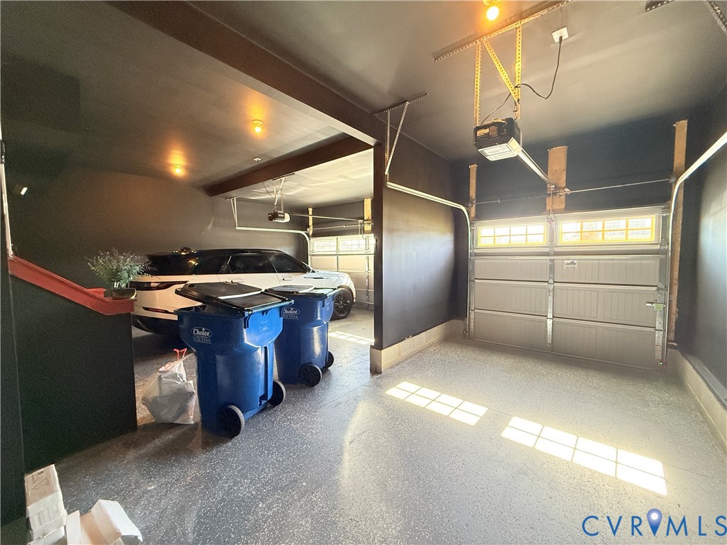 Multi-car garage featuring segmented overhead doors with paneled windows, high-contrast dark wall finish, and finished flooring