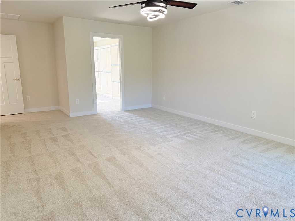 Neutral-toned carpeted flooring, multi-panel interior door, and modern ceiling fan with integrated circular LED lighting fixture