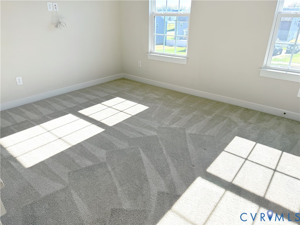 Neutral-toned carpeting featuring two double-hung windows with colonial muntins