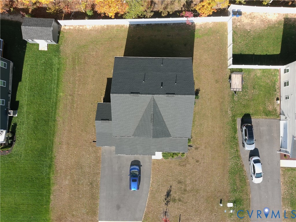 Aerial view of property featuring a detached storage shed, perimeter privacy fencing, and an asphalt driveway