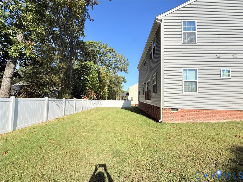 Expansive green lawn with a white privacy fence
