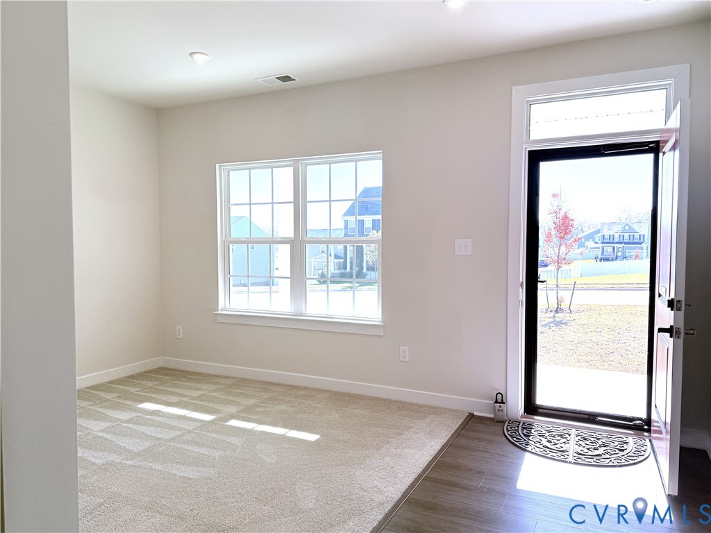 Neutral-toned wall-to-wall carpeting, wood-finish flooring, recessed lighting, double-hung windows with mullions, and a glass-panel entry door with a transom window