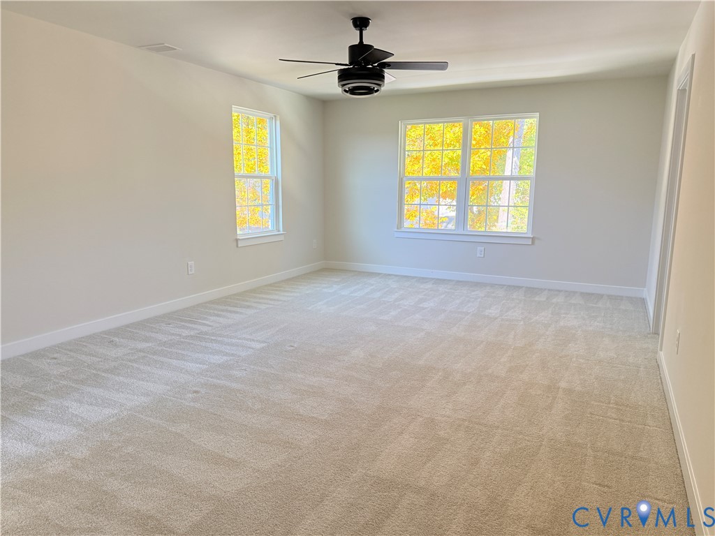 Neutral wall tones, wall-to-wall carpeting, multi-pane windows, and a ceiling fan with integrated lighting
