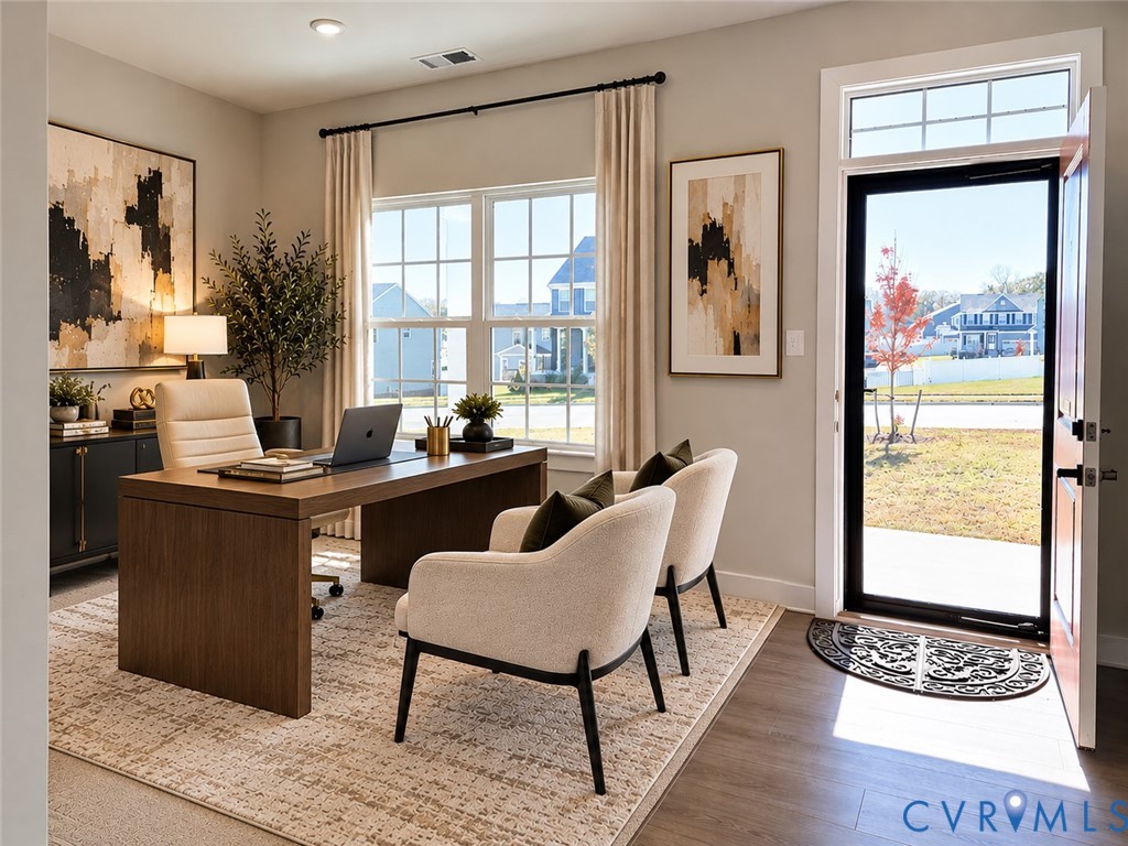 Neutral-toned interior room featuring wood-finish flooring, multi-pane windows, and a glass-paneled exterior door with a transom window